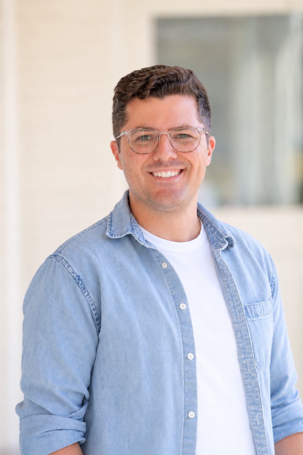 Jake Link smiling, wearing glasses and a light blue shirt